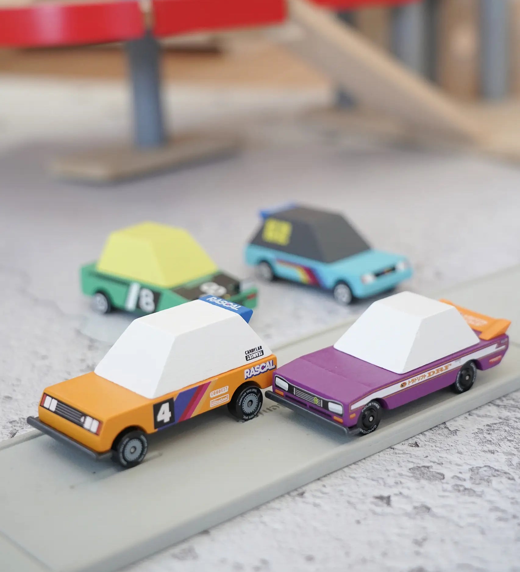 4 Candylab Tokyo heat toon cars on a play road with a parking garage in the background.