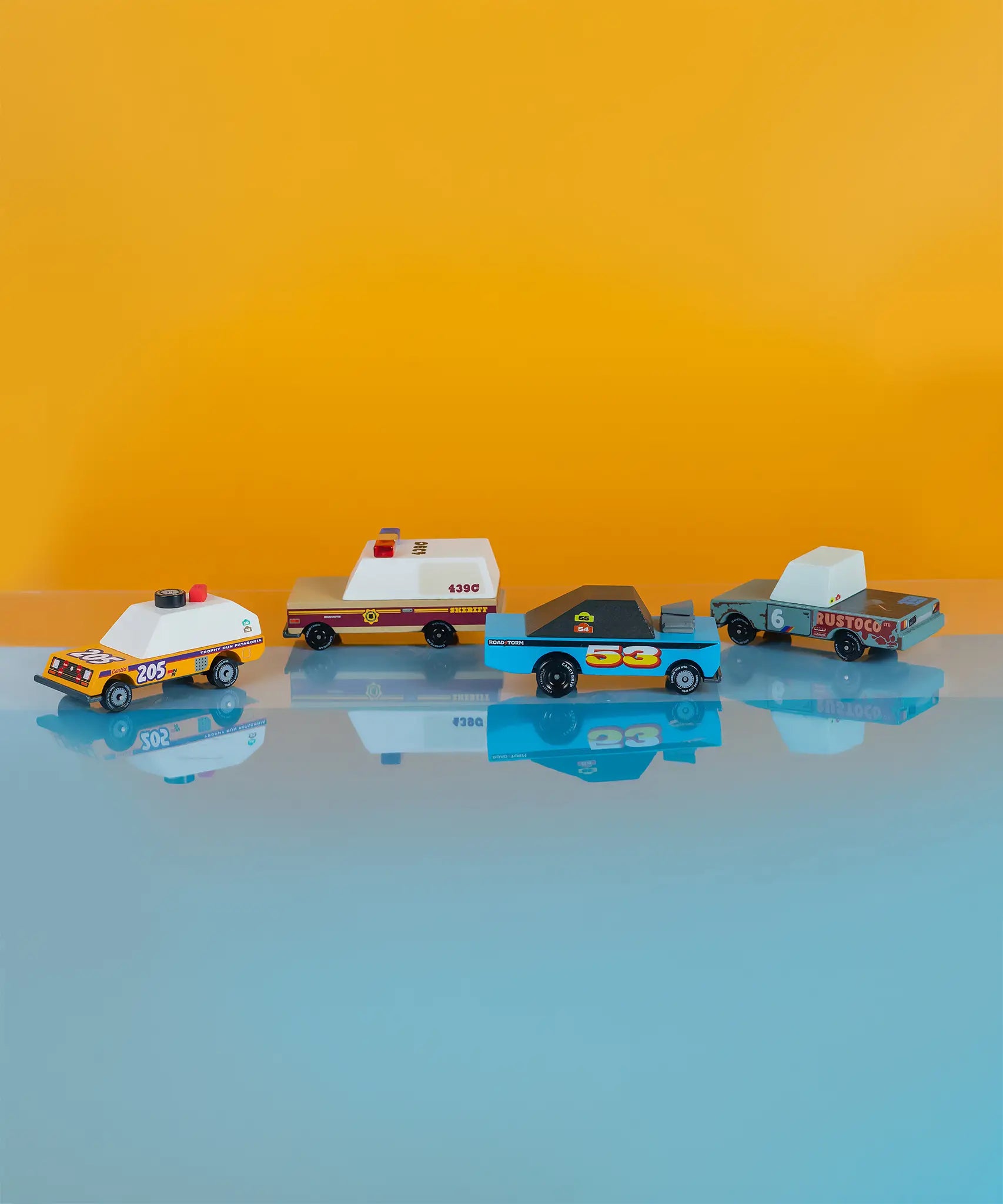 4 wooden diecast sturdy Candylab toon cars from the rust patrol set in front of a coloured background