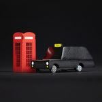 Candylab wooden London taxi car toy on a white snow scene background next to some miniature trees and red phonebox