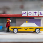 Close up of a Candylab children diecast taxi car in front of a toy motel