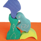 Pieces from the Grimm's casa aqua wooden toy stacking puzzle stacked up high. Four piece simple wooden block puzzle toy in a mix of blue and green colours. 