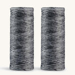 A pair of charcoal floss refills on a cream background