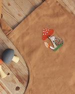 embroidered hedgehog and mushroom pattern of the chest of the apron.