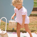 Two children holding the Olli Ella Rattan Berry Basket with Lining – Pansy Floral and Gumdrop in their hands. Inside each basket are colourful pink