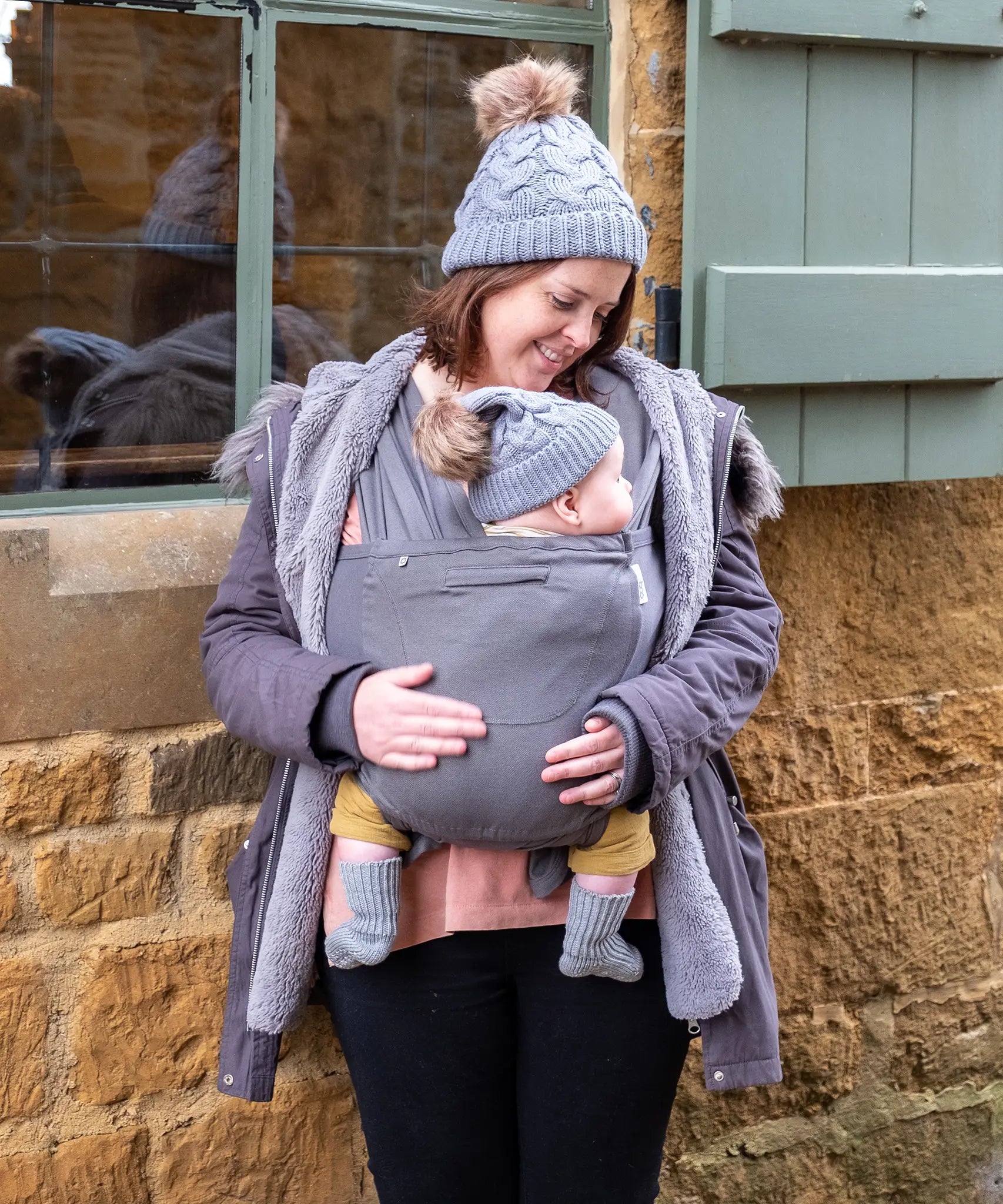 Front of mother carrying a baby in Close Caboo cotton blend soft structure Baby Carrier in olive