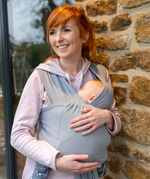 Woman babywearing with the Close Caboo Lite Baby Carrier in Alloy worn in front carry, showing a sleeping newborn supported close to the her.