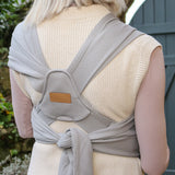Back of woman wearing a Close Caboo Organic Baby Carrier in porpoise  showing wide shoulder straps, tie waist strap, and soft supportive panel.