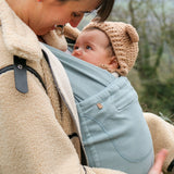 Side of mother carrier a baby in a Close Caboo Organic Baby soft structure cotton Carrier in sage