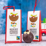 2 Cocoa Loco giant christmas chocolate pudding truffles on a white and blue background next to a glass bauble