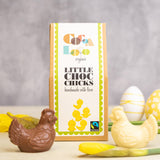 Cocoa Loco eco-friendly fairtrade milk and white chocolate chickens on a cream worktop next to some white and yellow easter eggs and daffodils