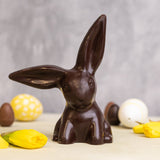 Cocoa Loco fairtrade dark chocolate easter rabbit on a beige worktop next to some mini easter eggs and daffodils