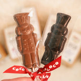 Close up of hand holding the Cocoa Loco fairtrade Christmas soldier lollies in front of some Cocoa Loco chocolate boxes.