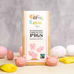 Cocoa Loco eco-friendly raspberry chocolate pigs on a cream worktop next to some pink and white easter eggs and daffodils
