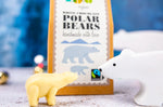 Close up of a Cocoa Loco white chocolate polar bear next to a wooden toy polar bear in front of its cardboard box