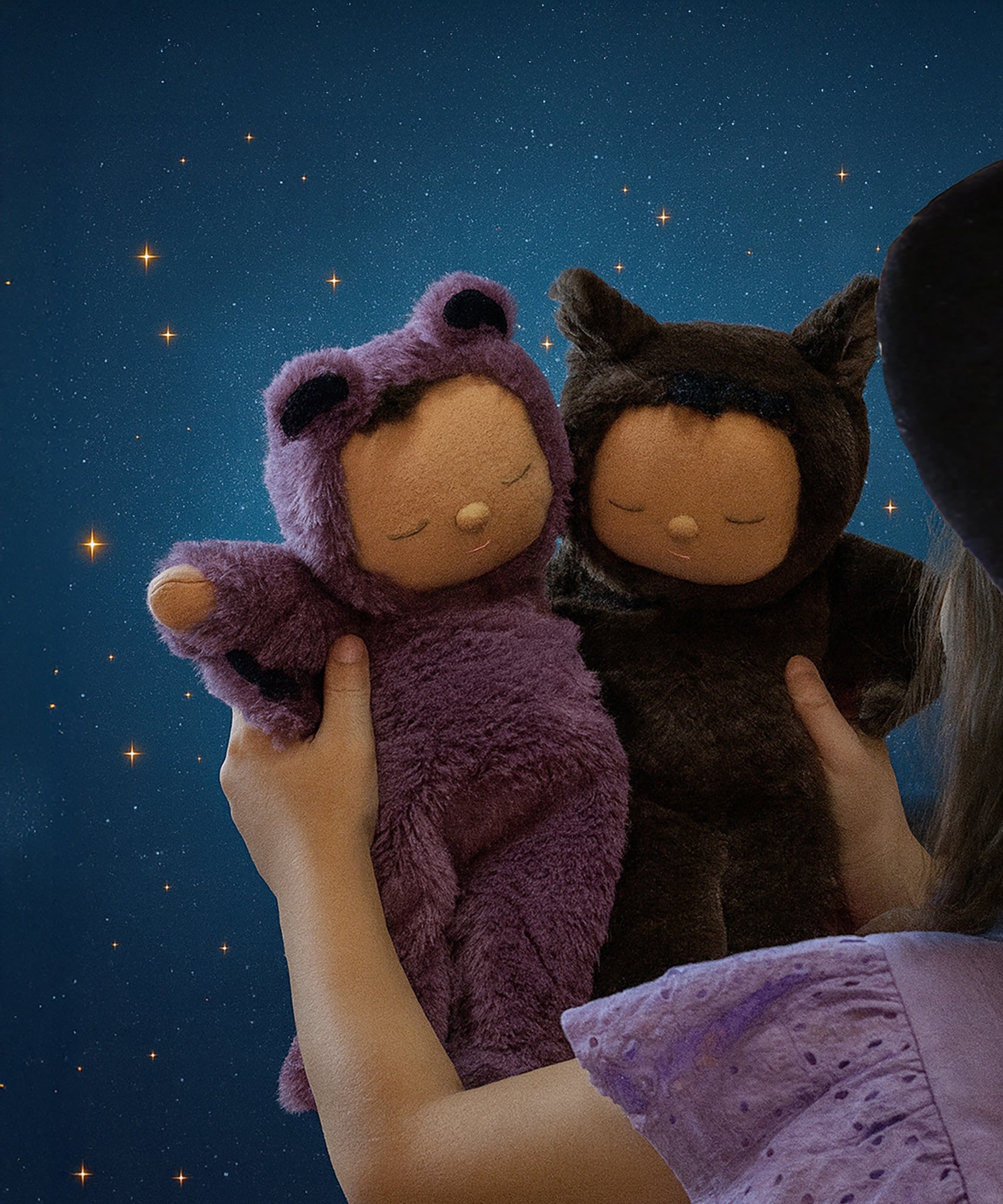A child holding up the two Olli Ella Cozy bat dinkum dolls. Ozzy a umber brown coloured bat and Pip a purple bat. These soft toys are part of Olli Ella's Halloween collection available here at Babipur.