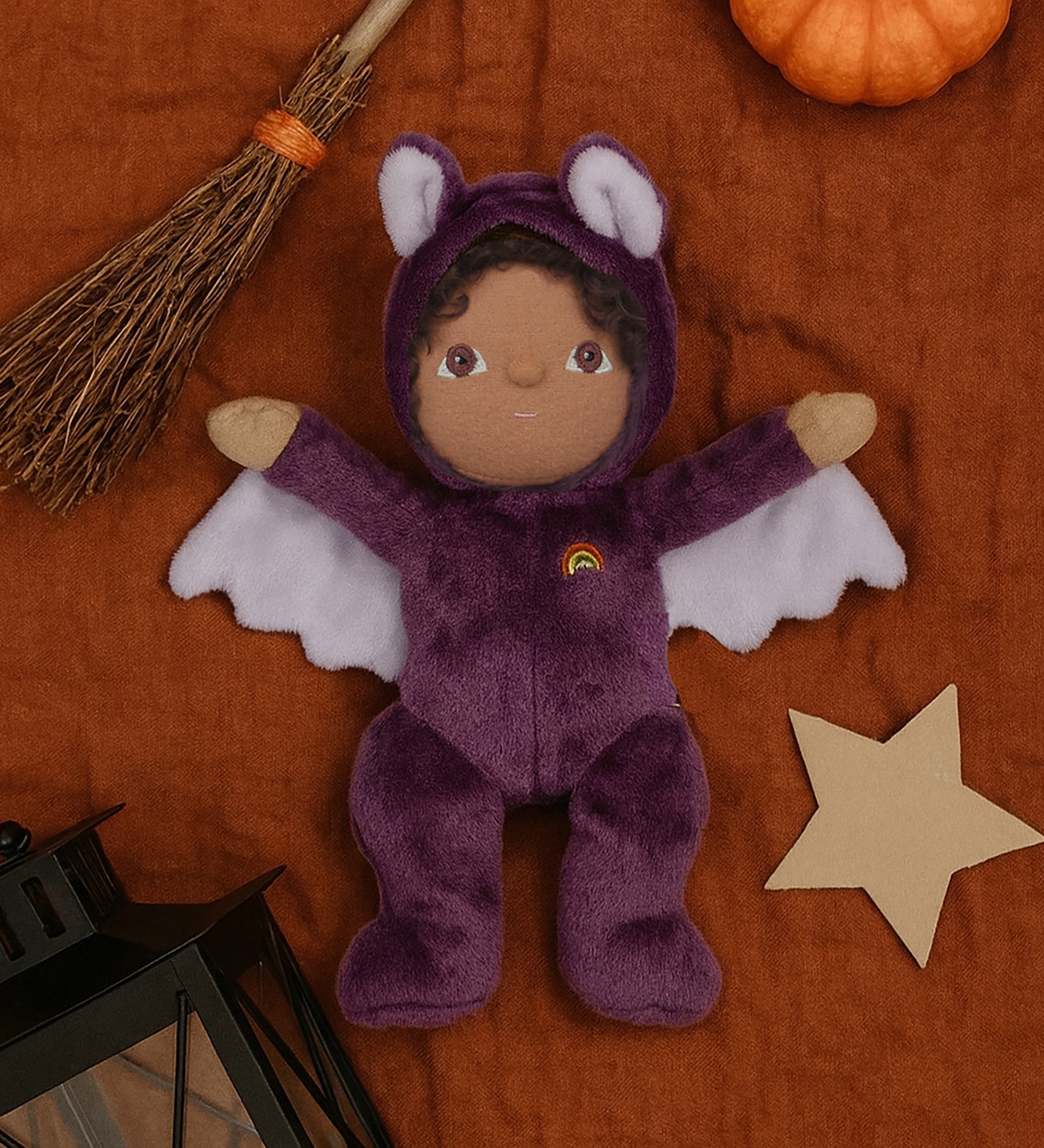 A purple coloured Olli Ella Bowie bat dinky dinkum doll soft toy. The dinky has dark coloured hair and lilac coloured inner wings and ears that glow in the dark. These soft toys are part of Olli Ella's Halloween collection available here at Babipur.
