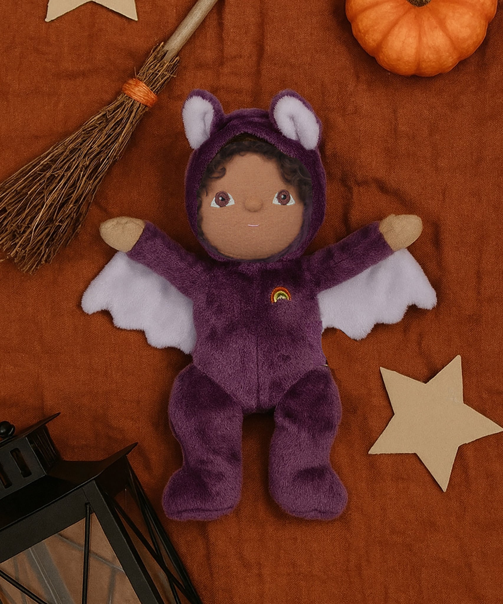A purple coloured Olli Ella Bowie bat dinky dinkum doll soft toy. The dinky has dark coloured hair and lilac coloured inner wings and ears that glow in the dark. These soft toys are part of Olli Ella's Halloween collection available here at Babipur.