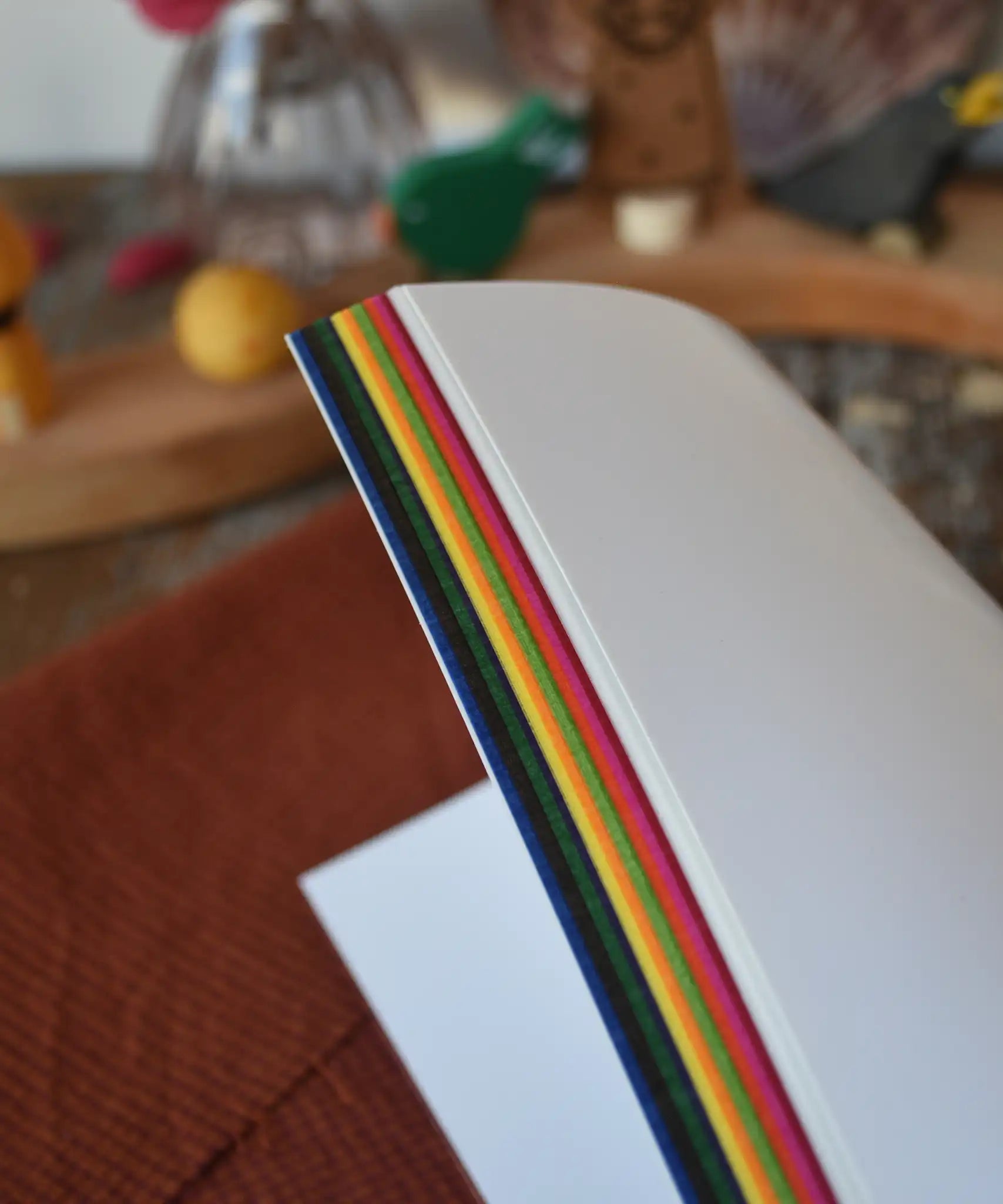 Kite paper squares for crafting. Book of 100 22cm square sheets in various colours. View of side of sheets.