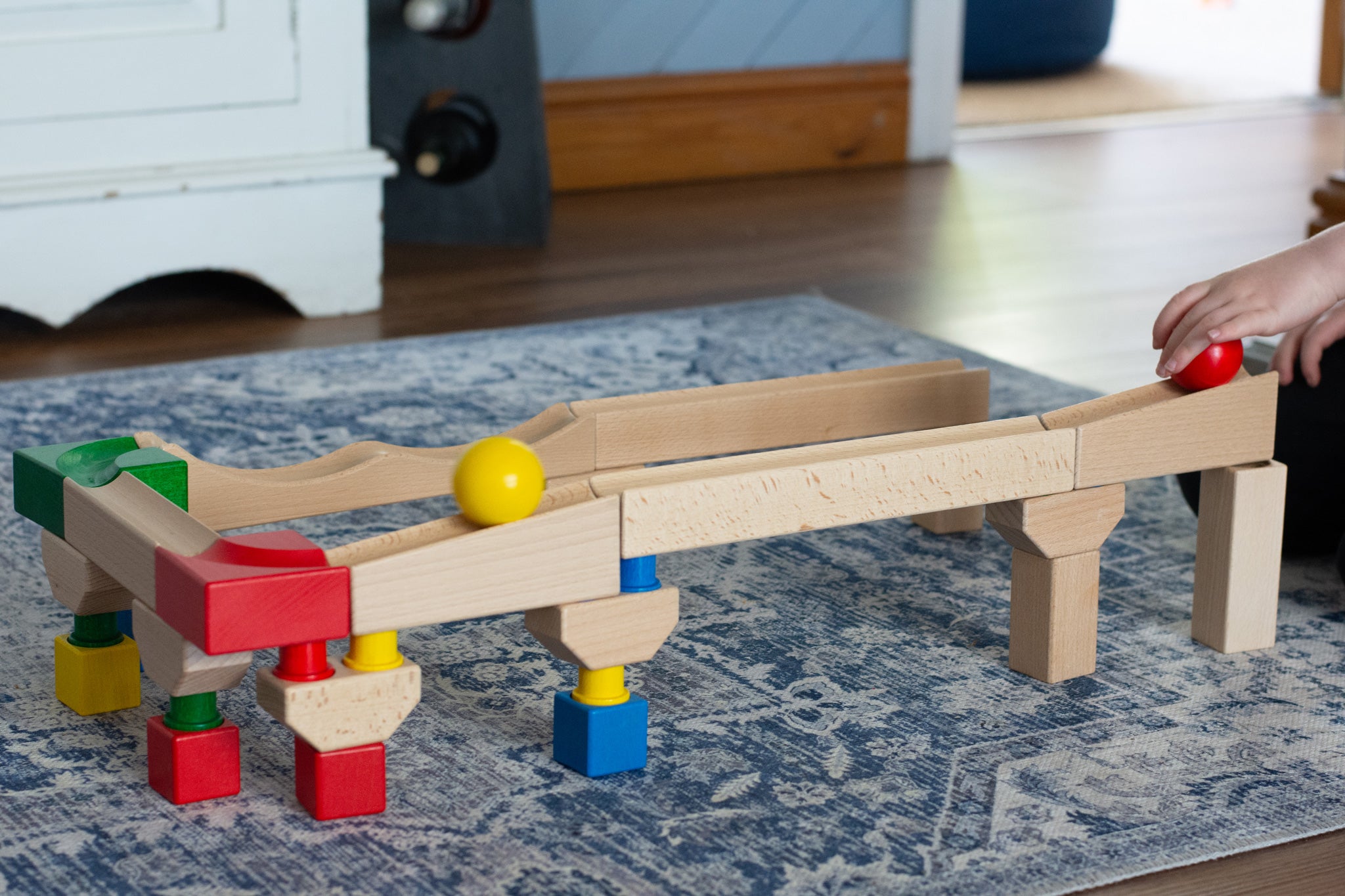 Nic Cubio wooden Ball Track Extension Set shown set up with a red  and yellow ball shown on motion on the track. Wooden balls are available to purchase separately. 