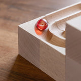 Close up of glass marble on a corner piece on the Cuboro duo wooden marble run set.