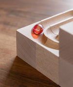 Close up of glass marble on a corner piece on the Cuboro duo wooden marble run set.