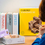 A close up of a child playing with the Cuboro wooden jump marble set. 