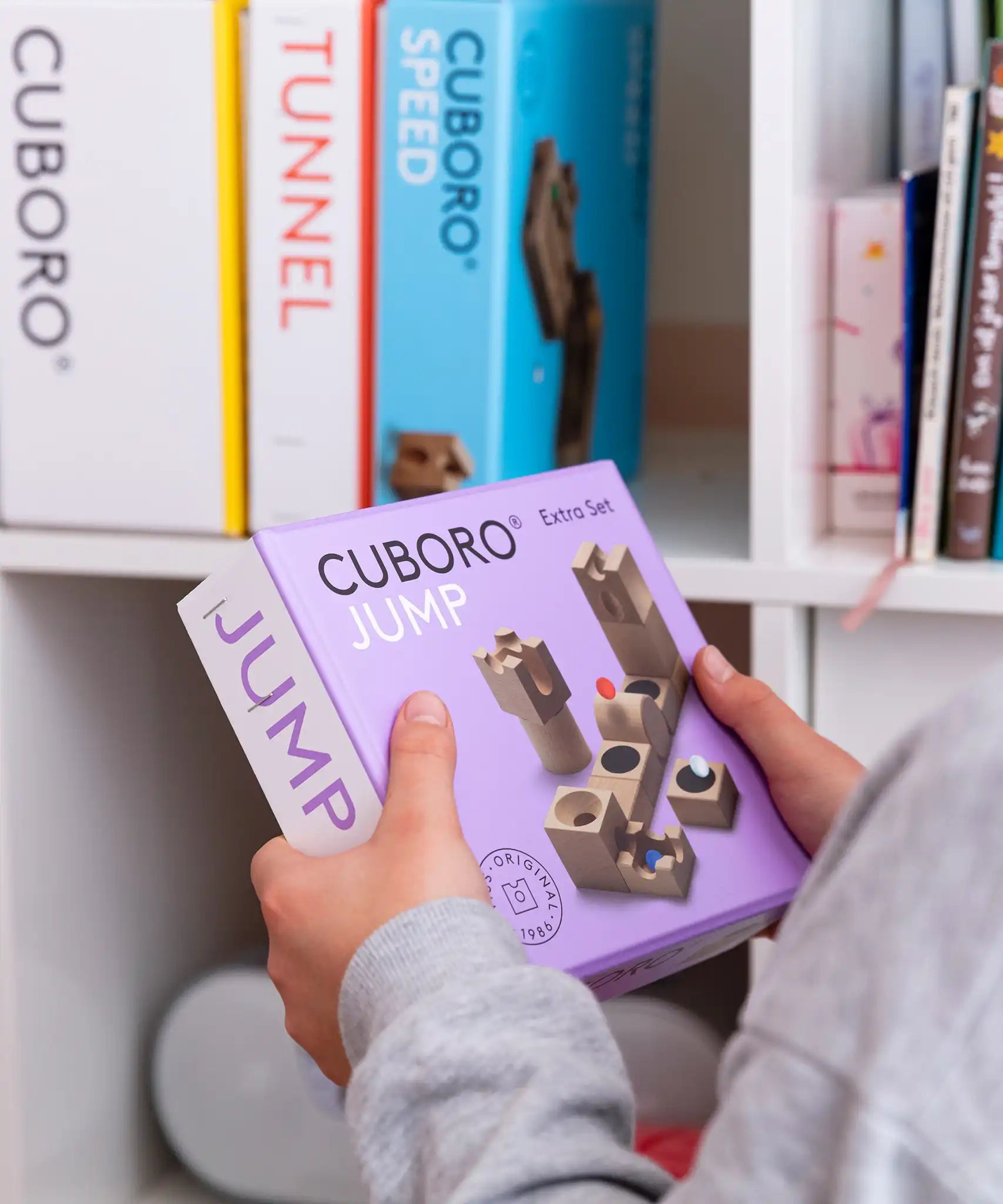 Cuboro Jump Wooden Marble Run Set in the packaging box in a child's hand.