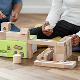 Close up of children playing with the Cuboro junior marble set, set up on the floor.