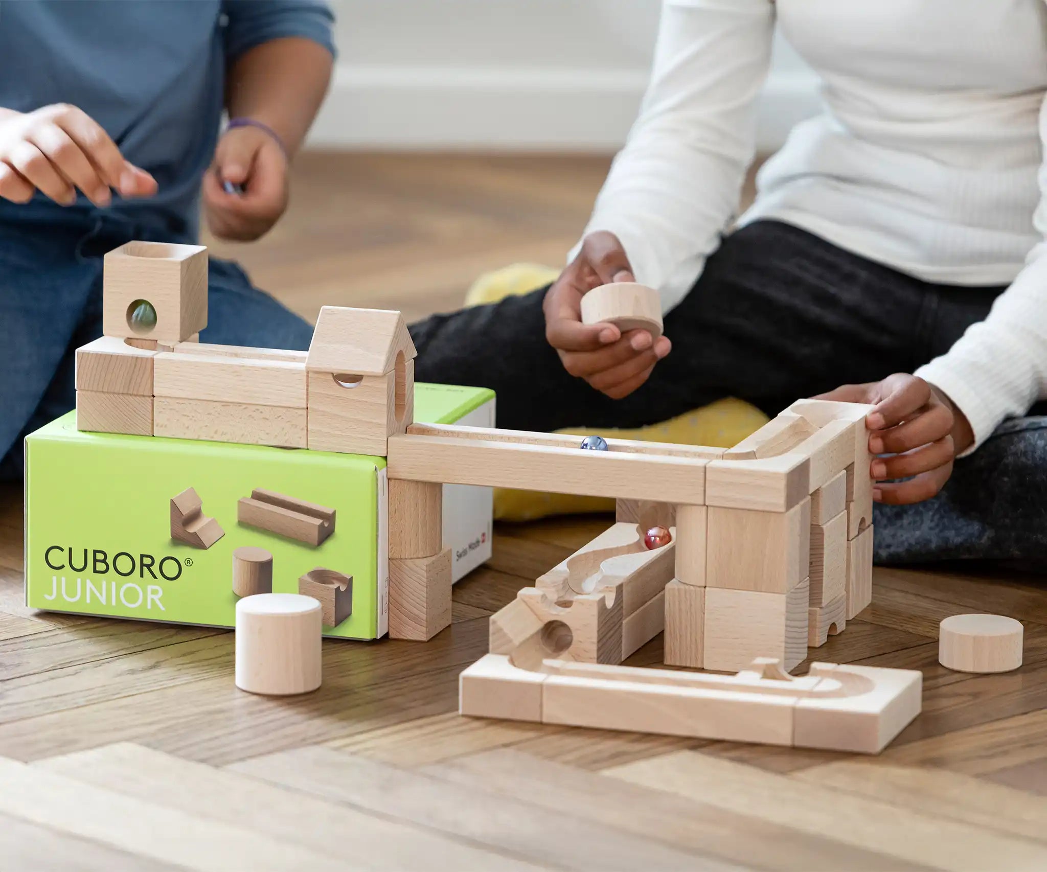 Close up of children playing with the Cuboro junior marble set, set up on the floor.