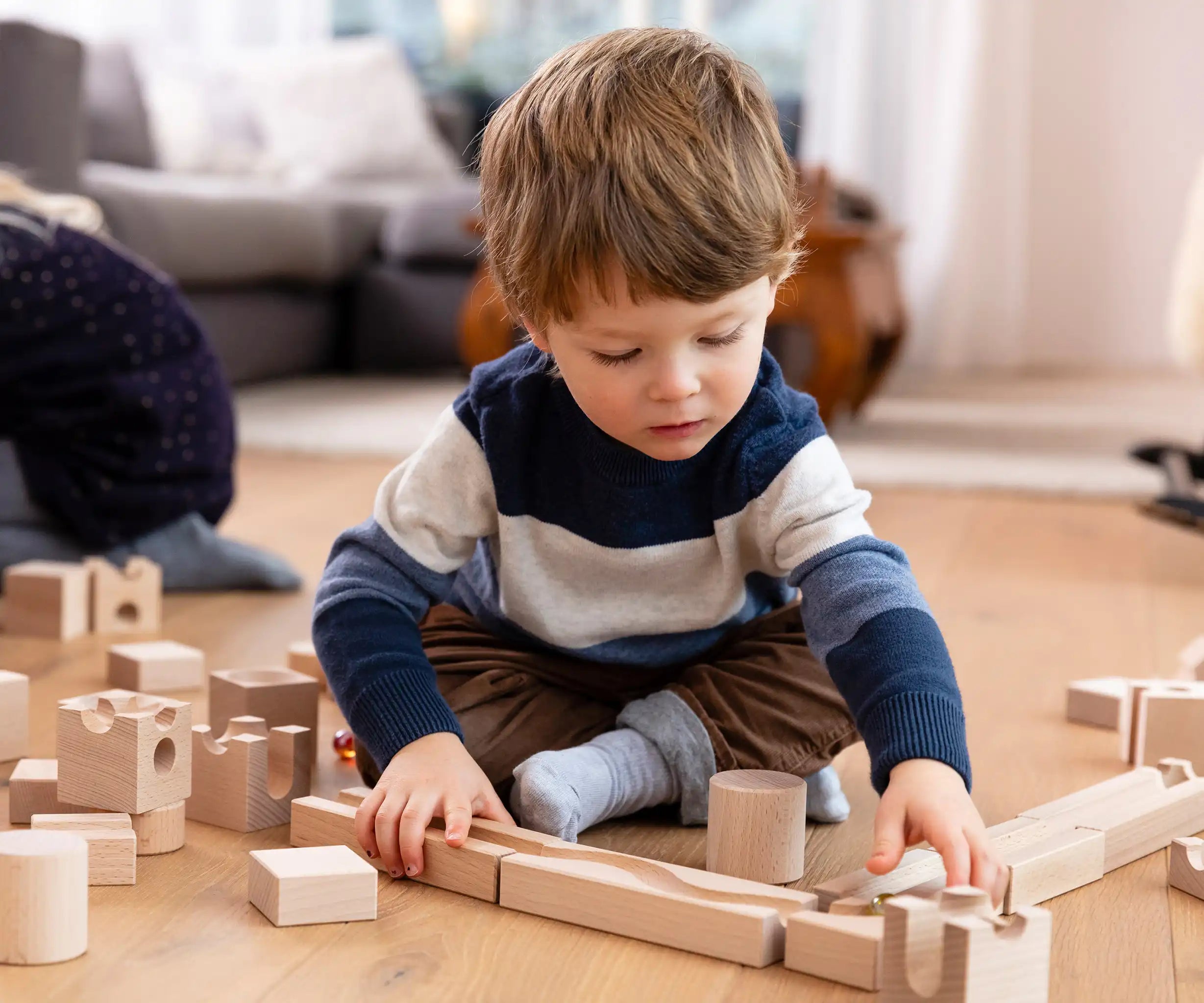 Child playing with the Cuboro junior marble set, set up on the floor.