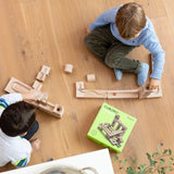 Children playing with the Cuboro junior marble set, set up on the floor. Overhead view