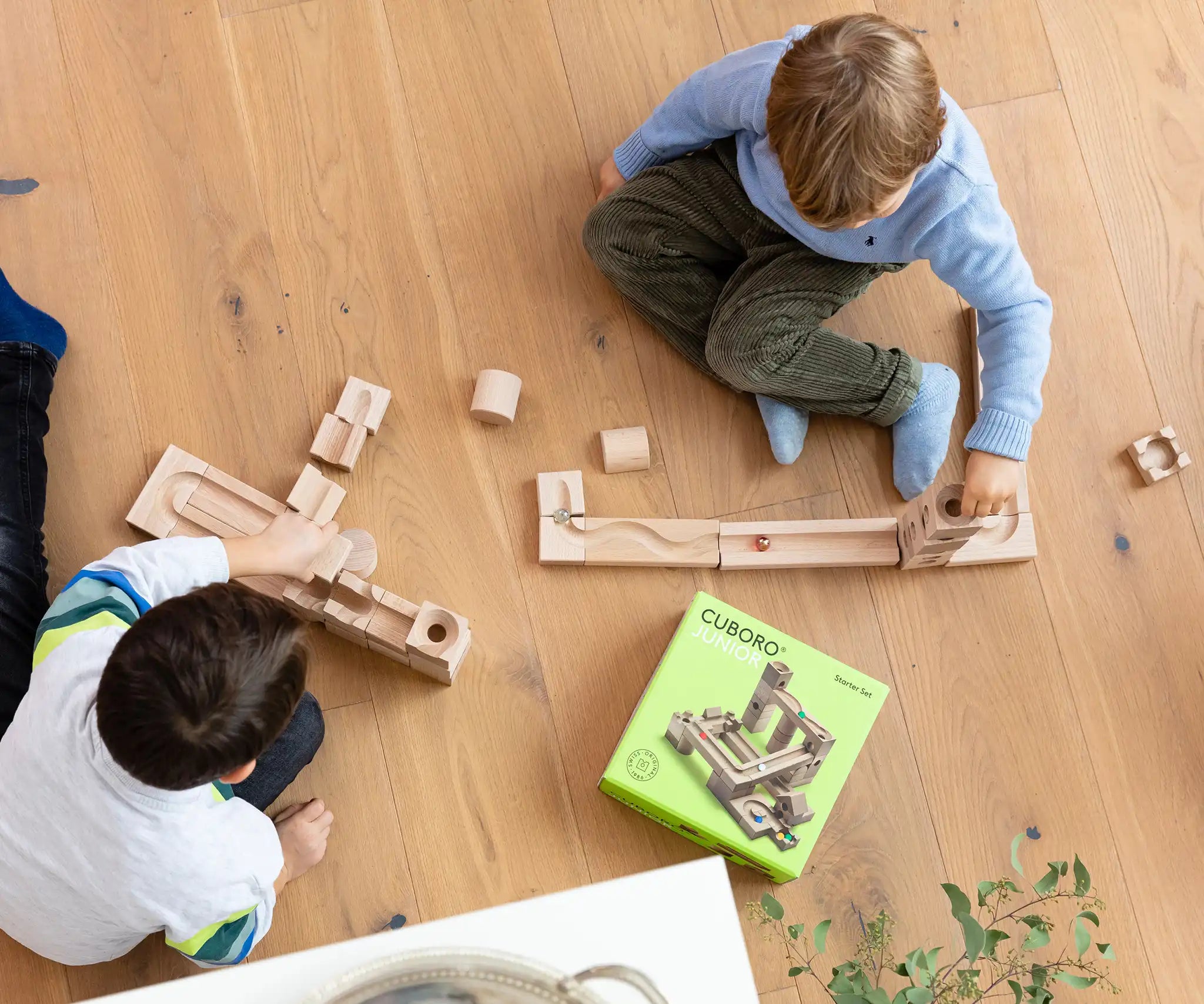 Children playing with the Cuboro junior marble set, set up on the floor. Overhead view