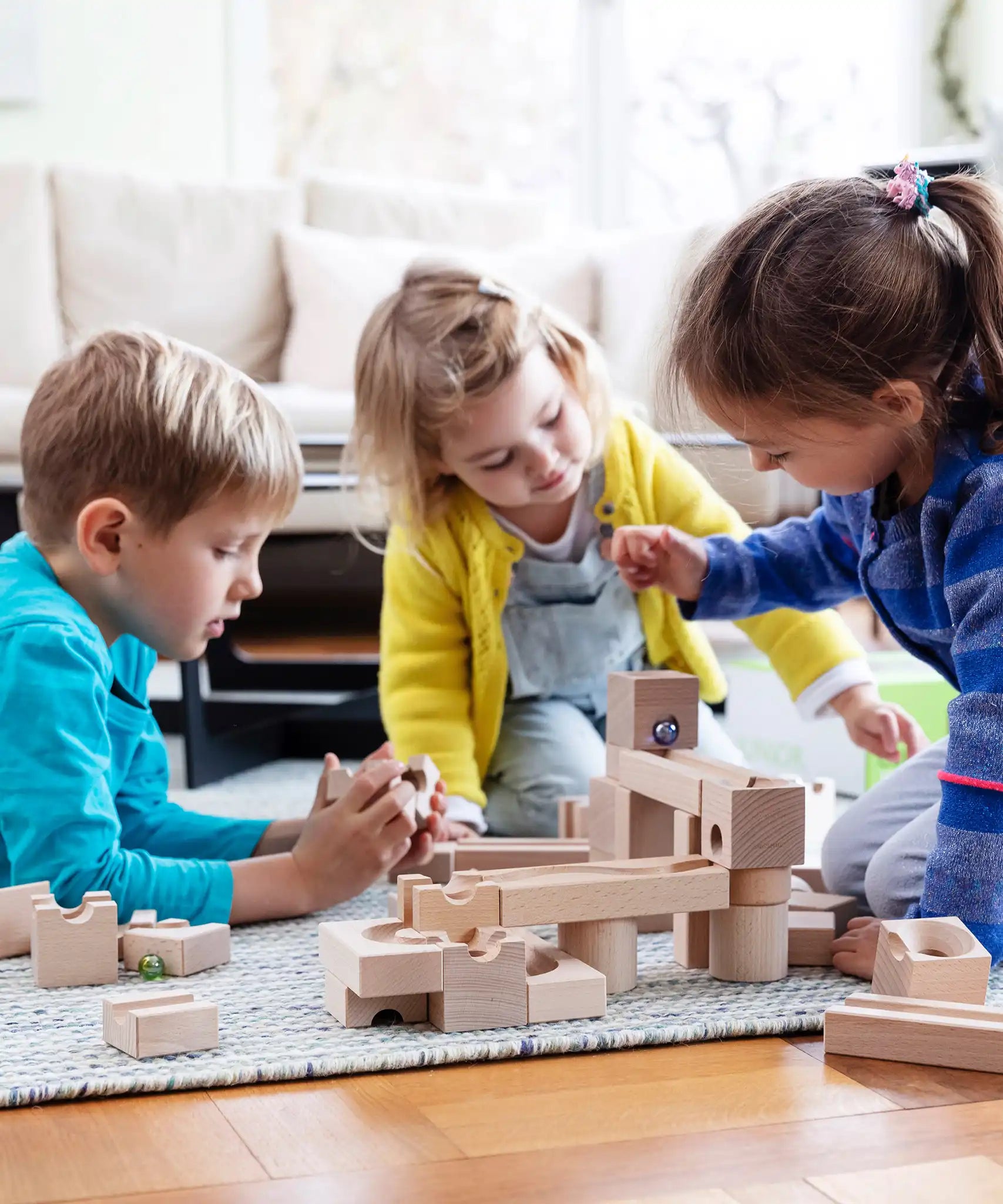 Children playing with the Cuboro junior marble set, set up on the floor.