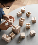 Cuboro standard 16 piece wooden marble run set being set up on a table by an adult. 