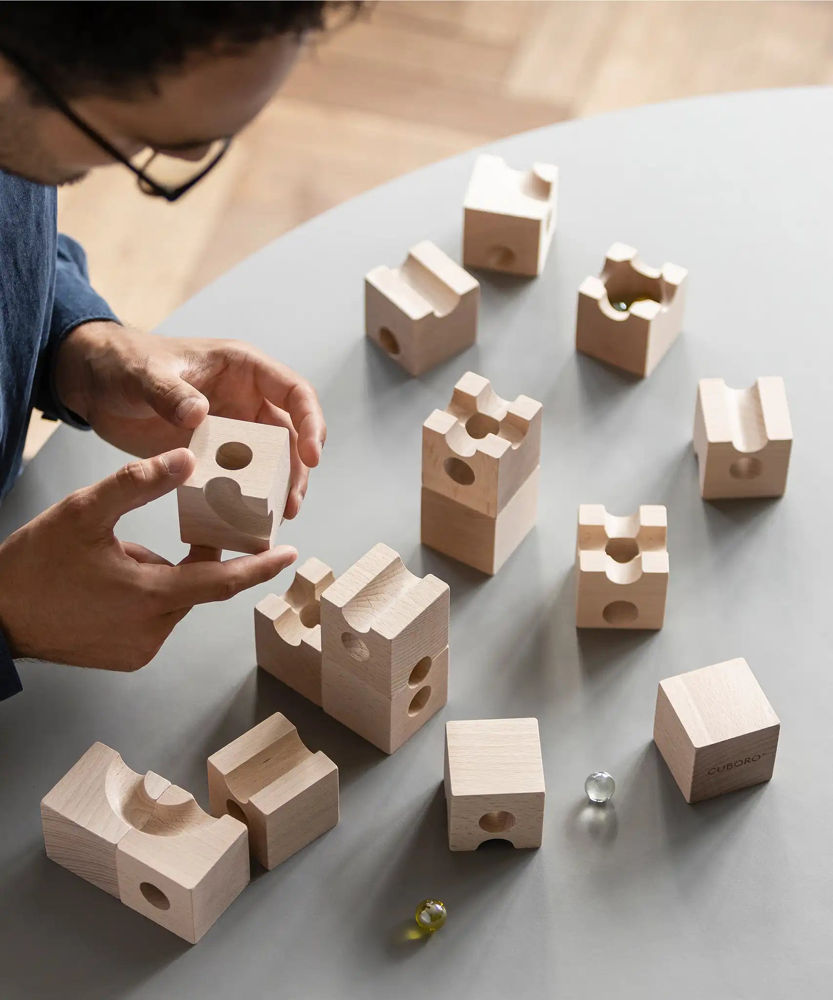 Cuboro standard 16 piece wooden marble run set being set up on a table by an adult. 