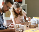 Cuboro standard 16 piece wooden marble run set being set up on a table by an adult and child.