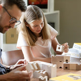 Cuboro standard 16 piece wooden marble run set being set up on a table by an adult and child.