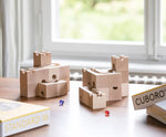 Cuboro standard 16 piece wooden marble run set up on a table with a blue and red glass marble placed besides them.