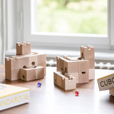 Cuboro standard 16 piece wooden marble run set up on a table with a blue and red glass marble placed besides them.