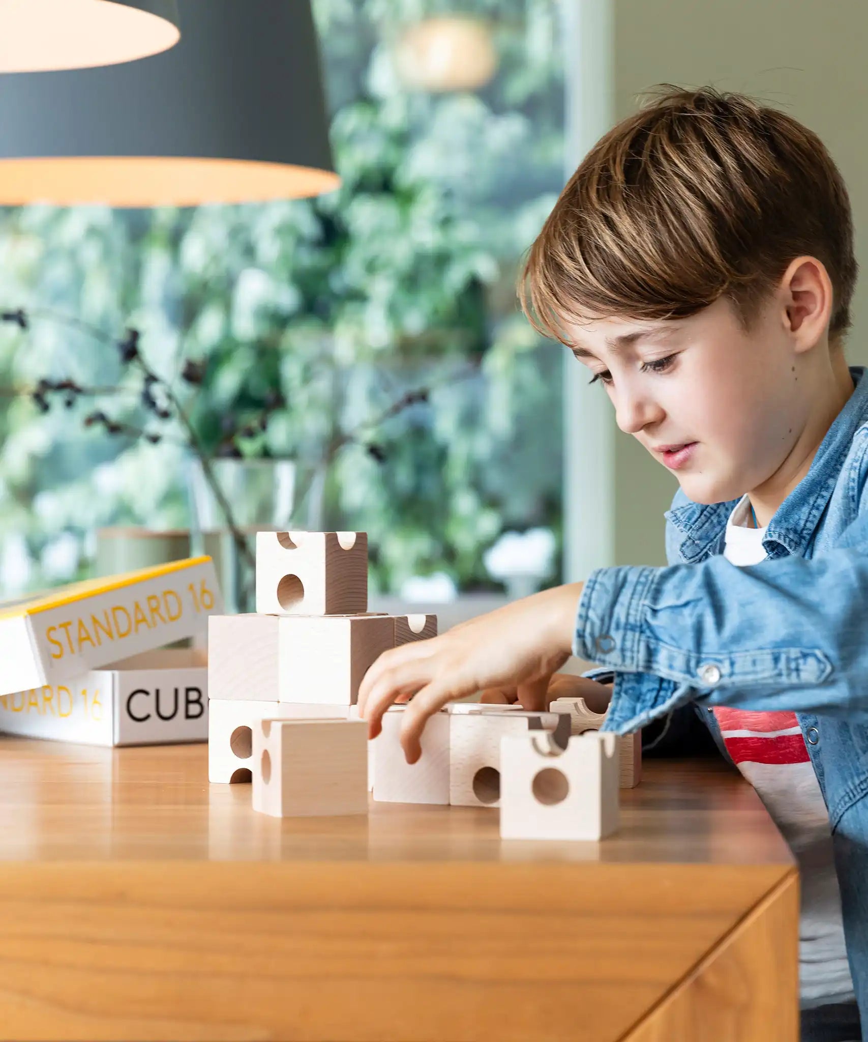 Cuboro standard 16 piece wooden marble run set up on a table, played with by a child. 