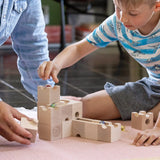 Cuboro standard 16 piece wooden marble run set played with by a child and an adult on the floor.