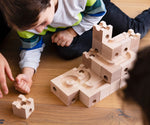 Cuboro Standard wooden marble run  32 piece set, set up on the floor with a child waiting for a marble to travel down the track.