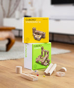 Boxes of the Cuboro Junior and Standard wooden marble run building kits on a wooden floor