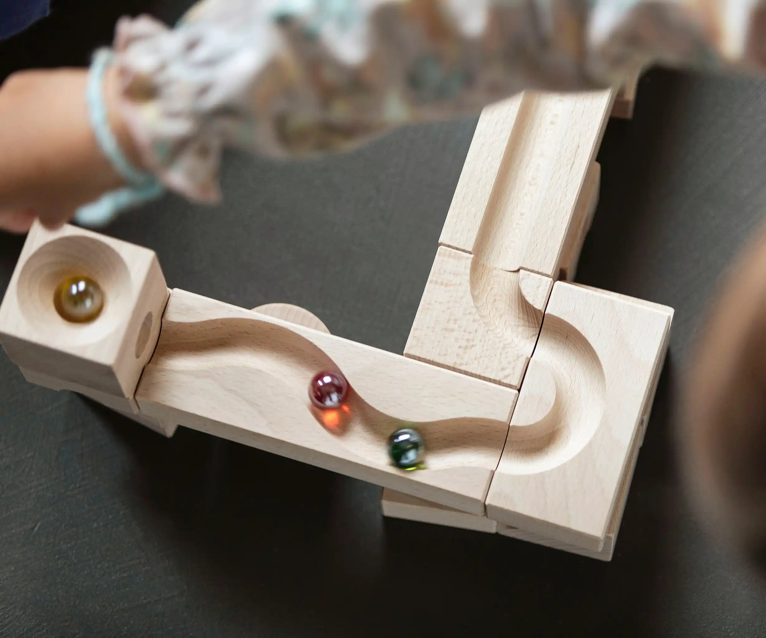 Close up of a child placing marbles on the Cuboro junior marble set, set up on the floor.
