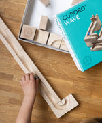 A child's hand placing a marble on the Cuboro Wave marble run set