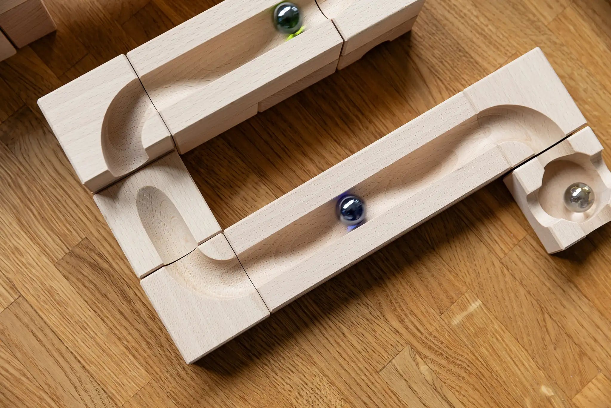 Cuboro Wave wooden marble run set up on the floor with marbles blurred in motion as they move down the track.