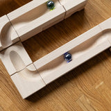 Cuboro Wave wooden marble run set up on the floor with marbles blurred in motion as they move down the track.