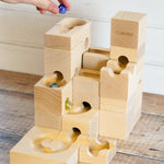 A Cuboro wooden standard marble run with marbles running on it on a wooden floor