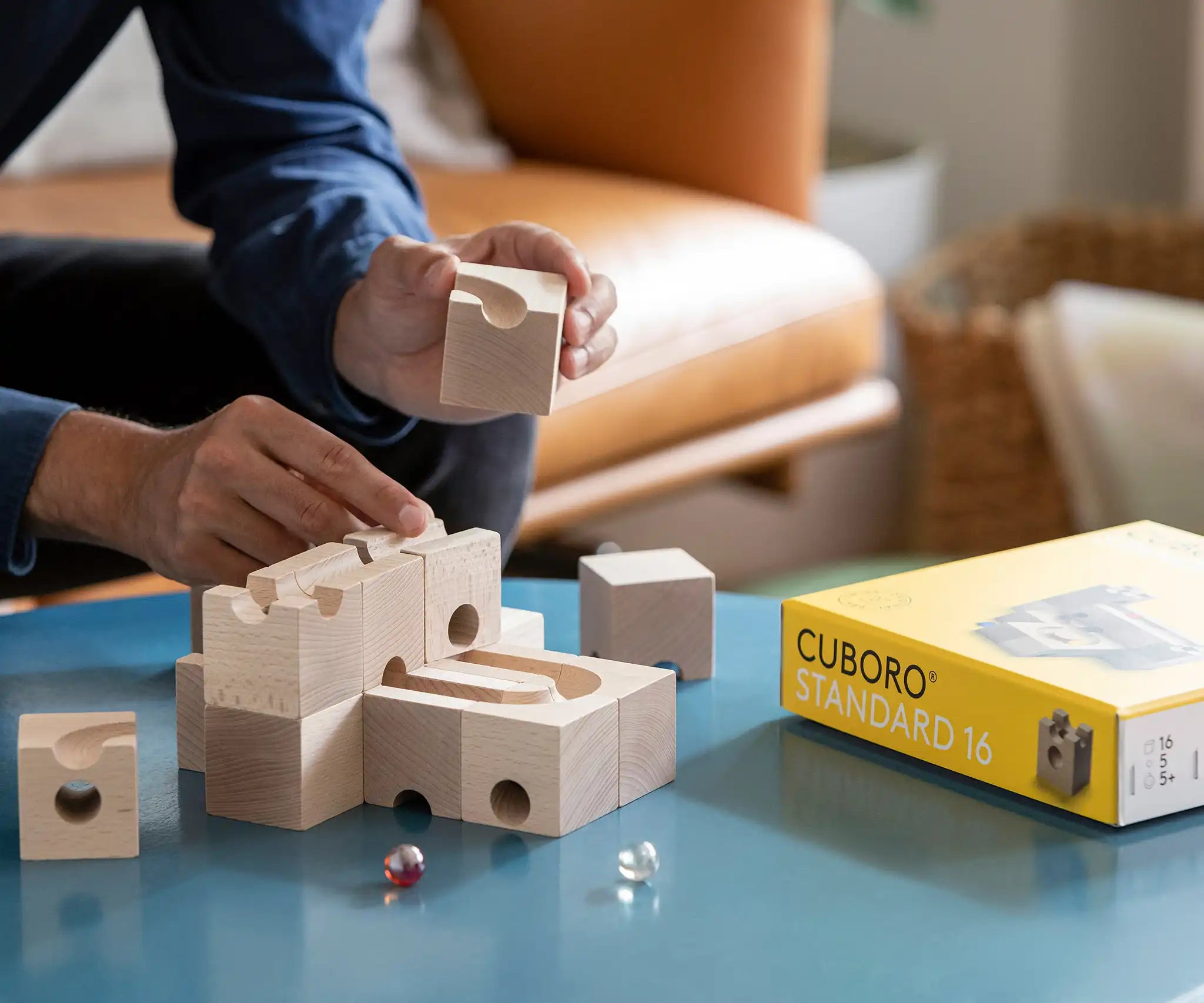Cuboro standard 16 piece wooden marble run set being built on a table by an adult.
