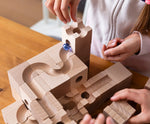 Child placing marbles in the Cuboro Standard wooden marble run  32 piece set, set up on a table.
